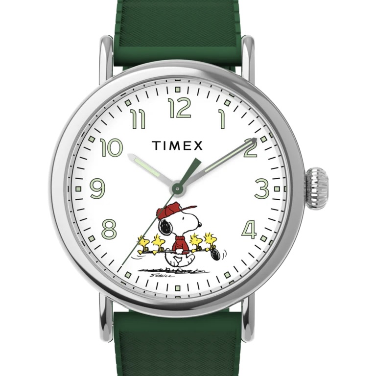 The Timex Peanuts Standard watch is white with green markings on the dial, features Snoopy wearing a hat and jacket, Woodstock and some of his friends, with a green synthetic band