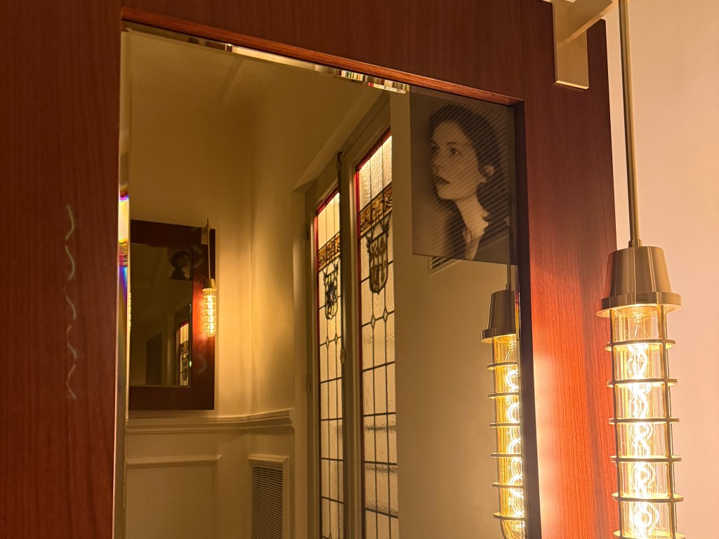 A detail in a mirror in the staircase show's the woman protagonist in the hotel's story