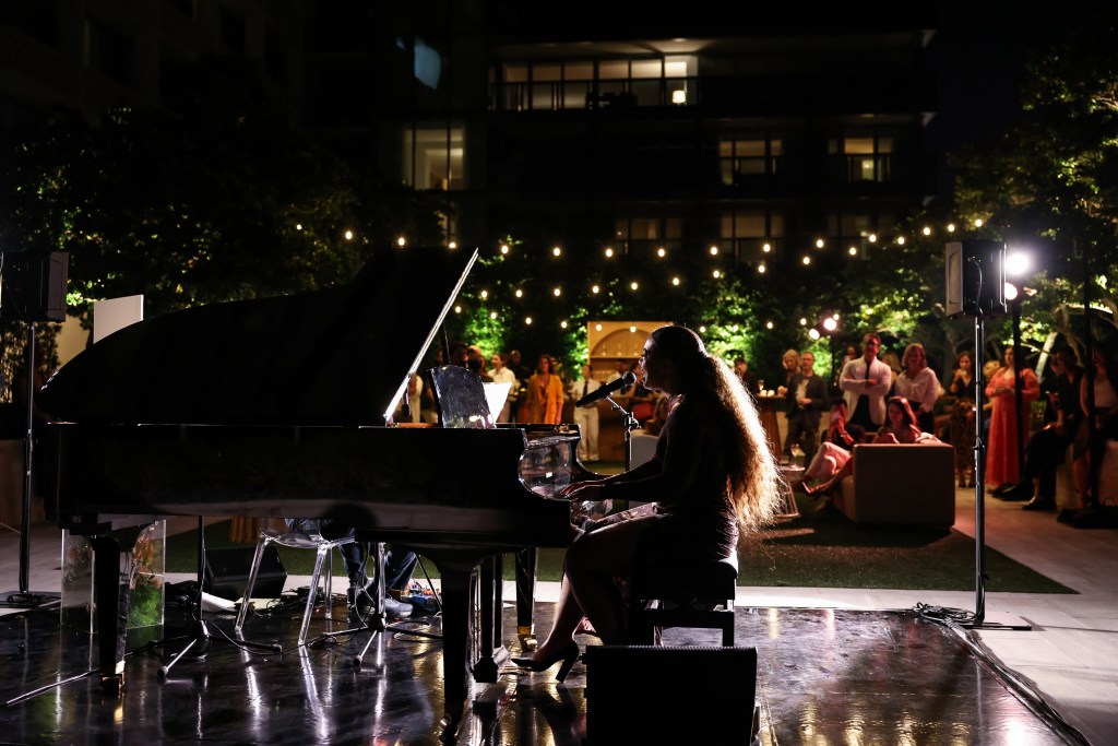 India Carney plays piano in front of guests at the event