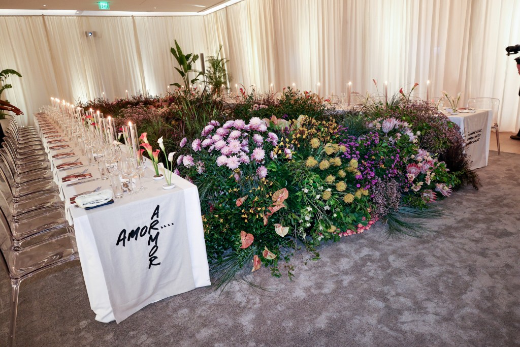 Event seating features white table cloths, candles, and an extremely large floral garden in between the two tables