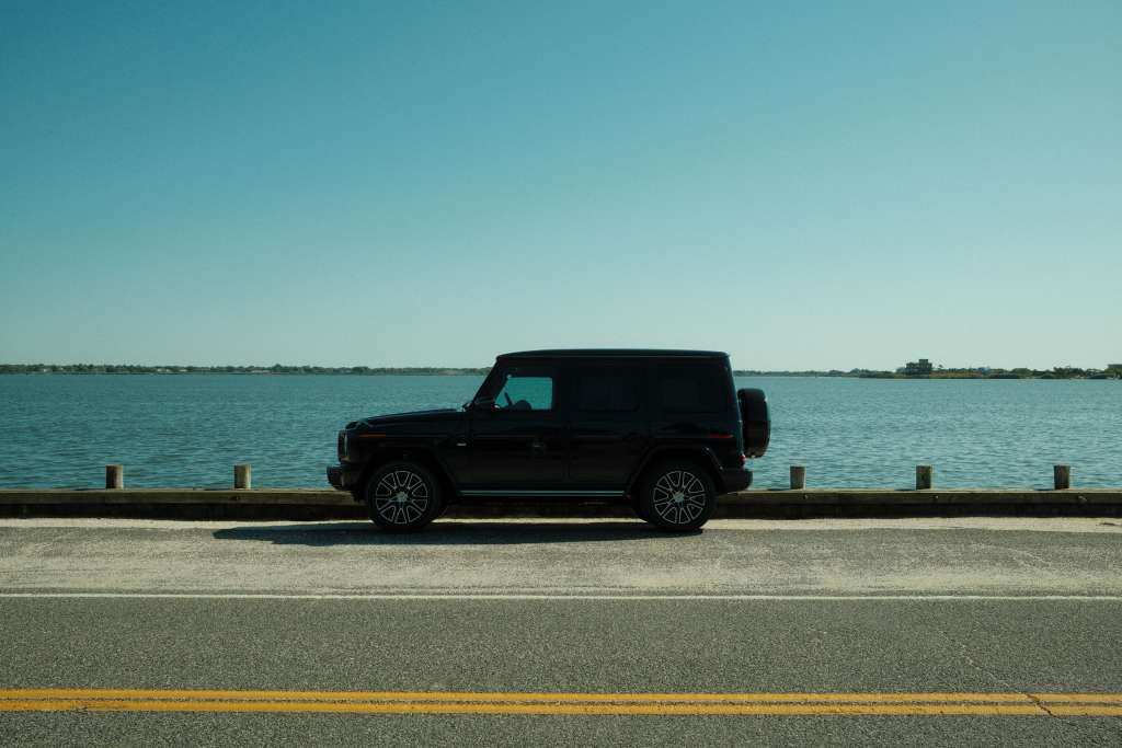 A Mercedes-Benz G-580 parked on an oceanside road with blue water in the background.