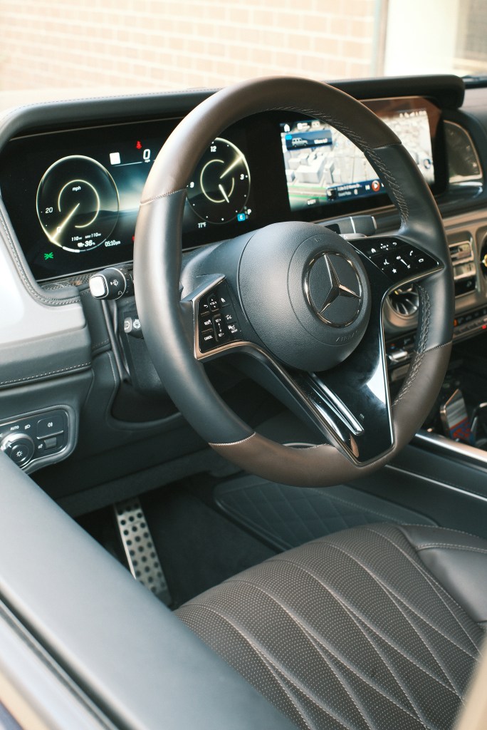 The interior of the Mercedes-Benz G-580, showing the driver's seat, steering wheel, dashboard and navigation system.