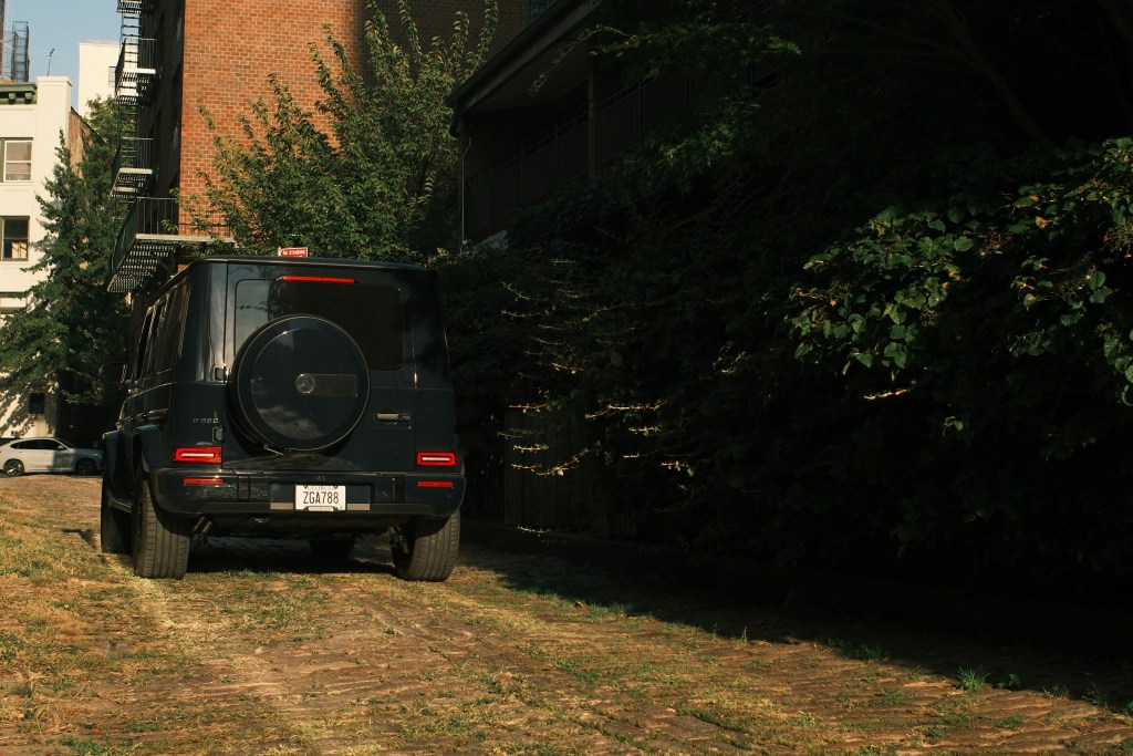 The back of a Mercedes-Benz G-580, parked by a brick building on a grassy lot.