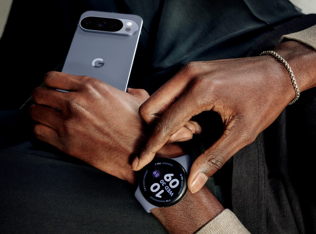 A closeup of a pair of hands, one holding a Google Pixel phone, one wearing a Googl Pixel 4 watch.