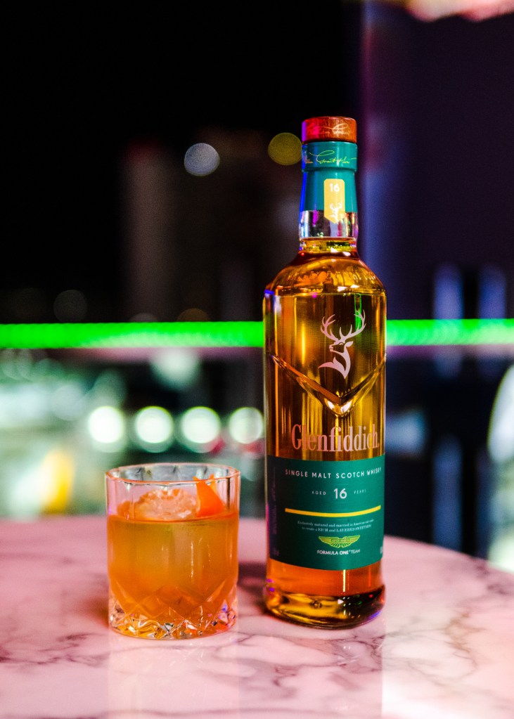 A bottle of Glenfiddich and Aston Martin limited edition 16-year single malt with a glass next to it. 