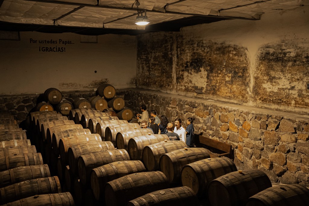 A group of people standing in a room of barrels.