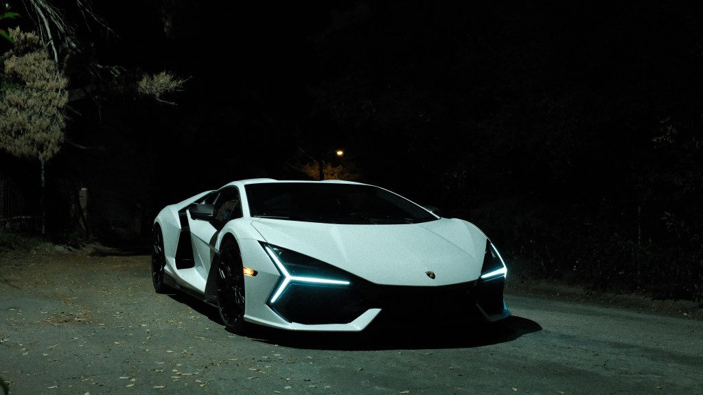 A white Lamburghini Revuelto on an asphalt road at night.