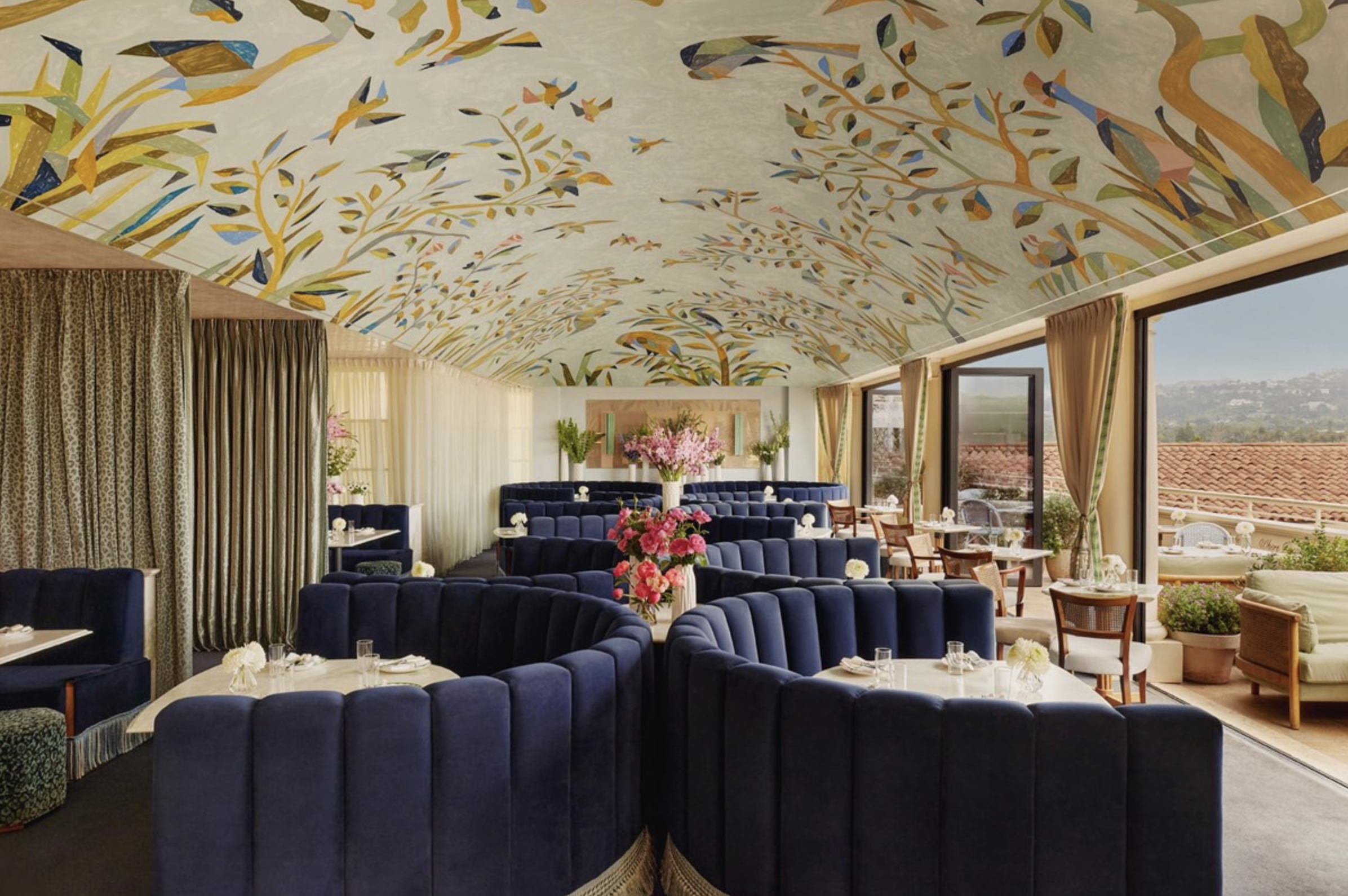 The Dante dining room at The Maybourne with round navy banquettes and a curved ceiling covered in floral wallpaper.