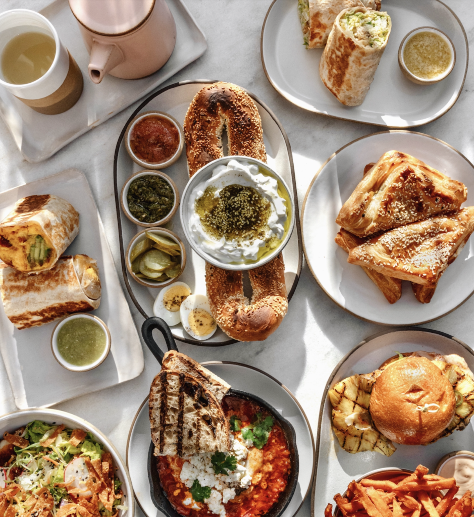 An overhead shot of plated breakfast foods on white plates and a white table with natural light.