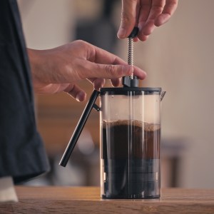 Weber Workshop's RoadRunner coffee press is shown on a table top with a man's hands on the press