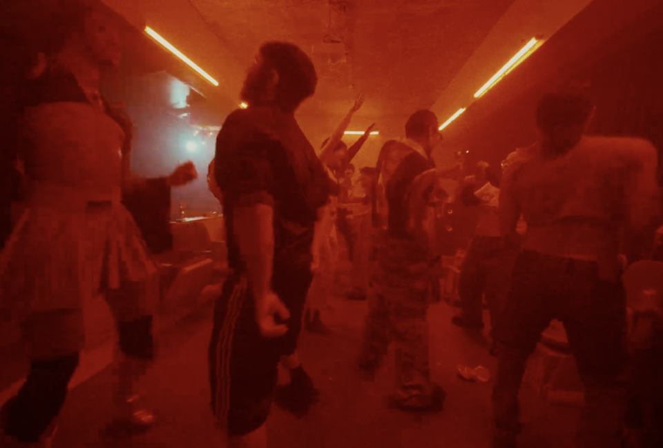 A red lit room with a group of people dancing.