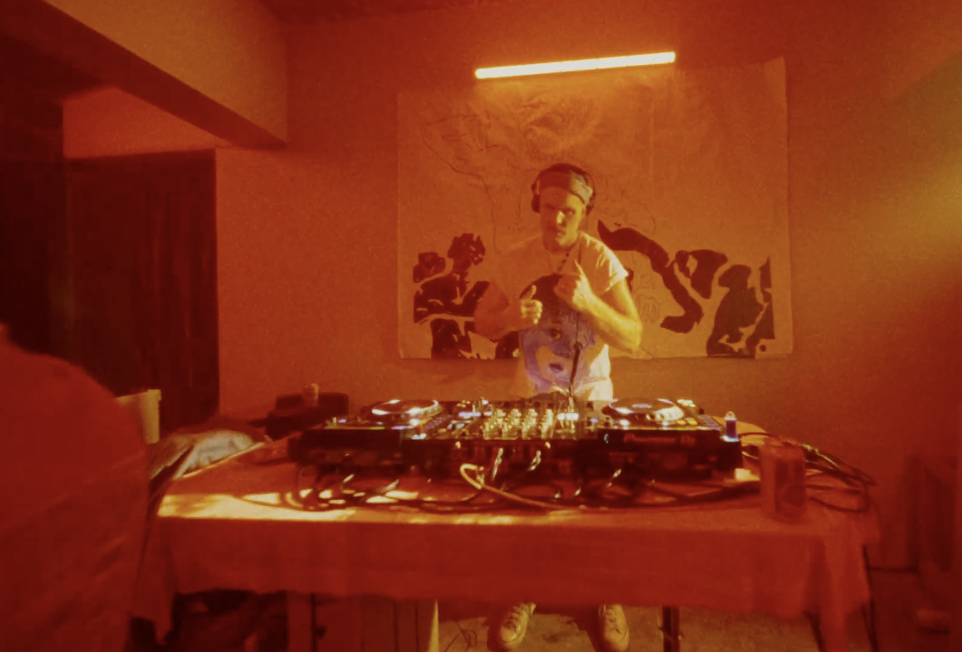 A DJ playing records in a red lit room.