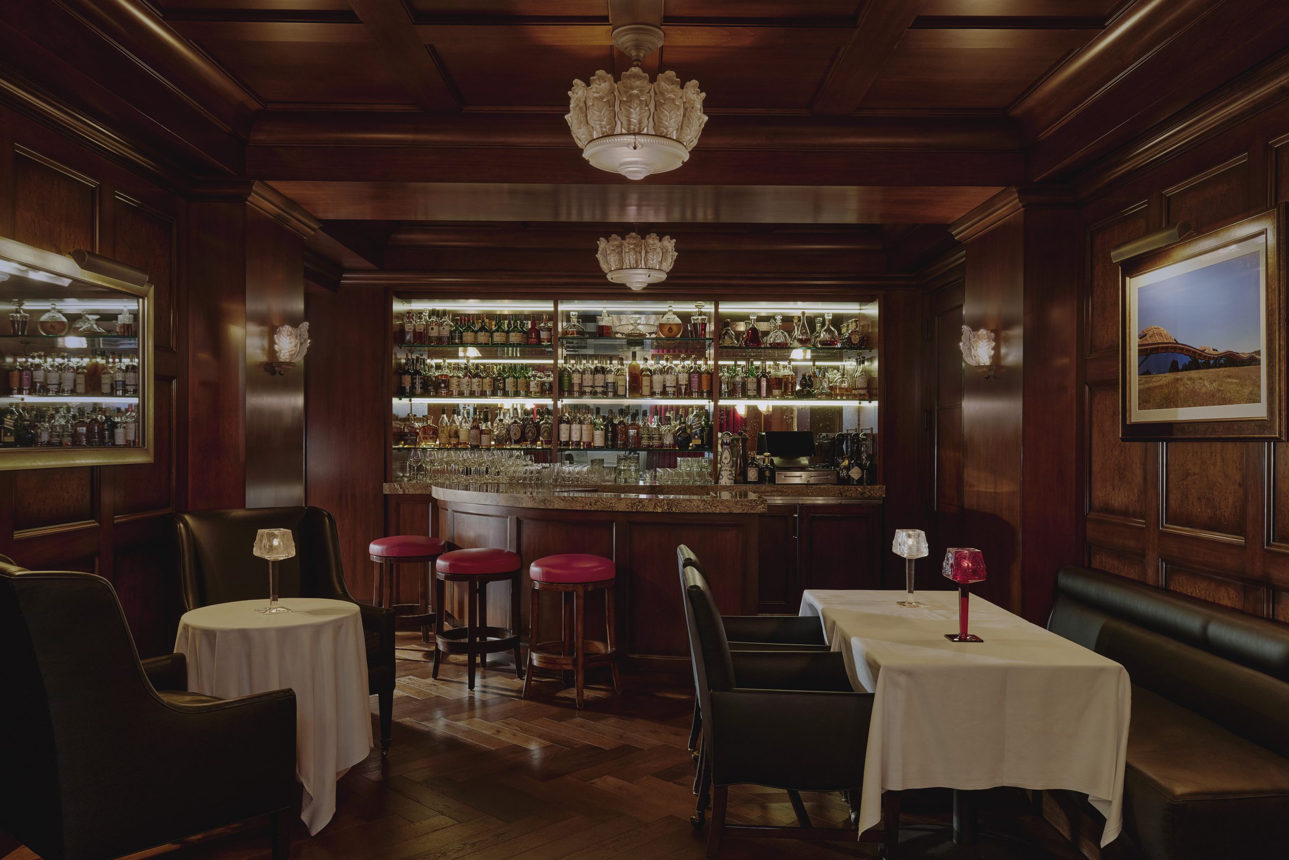 A dark bar room with a wall full of whisky bottles.