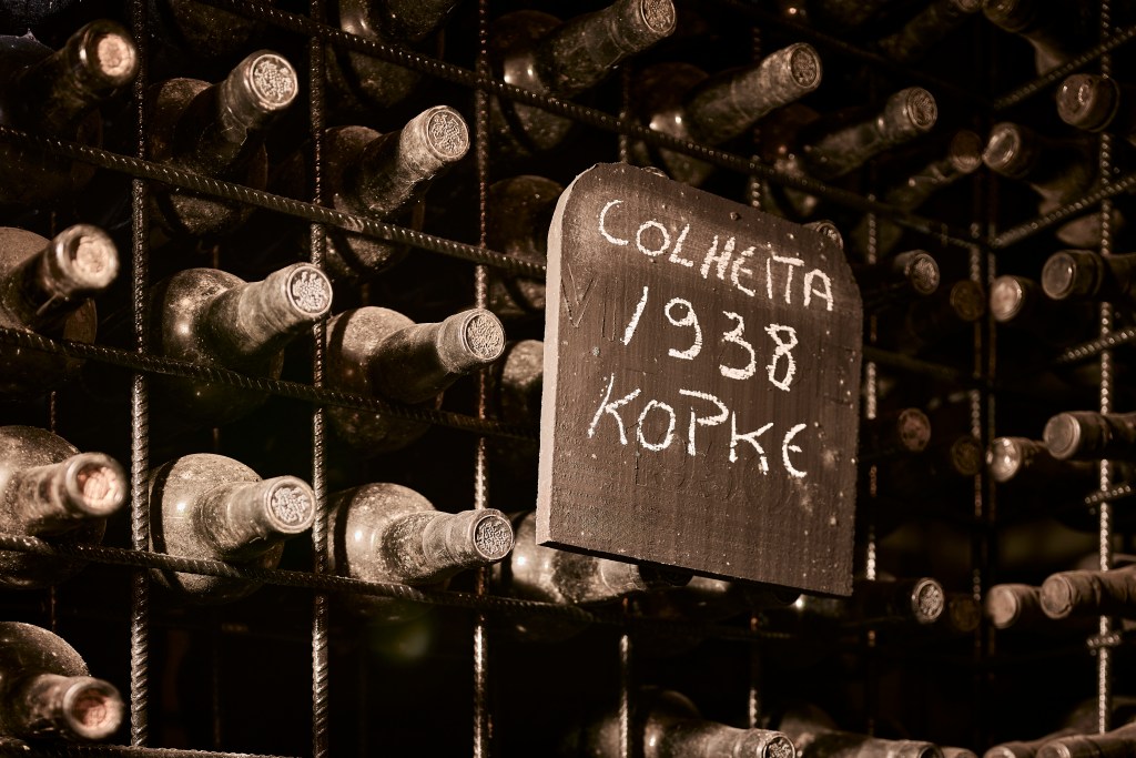 A chalkboard sign that says "Colheita 1938 Kopke" marks the rack of vintage bottles of port.