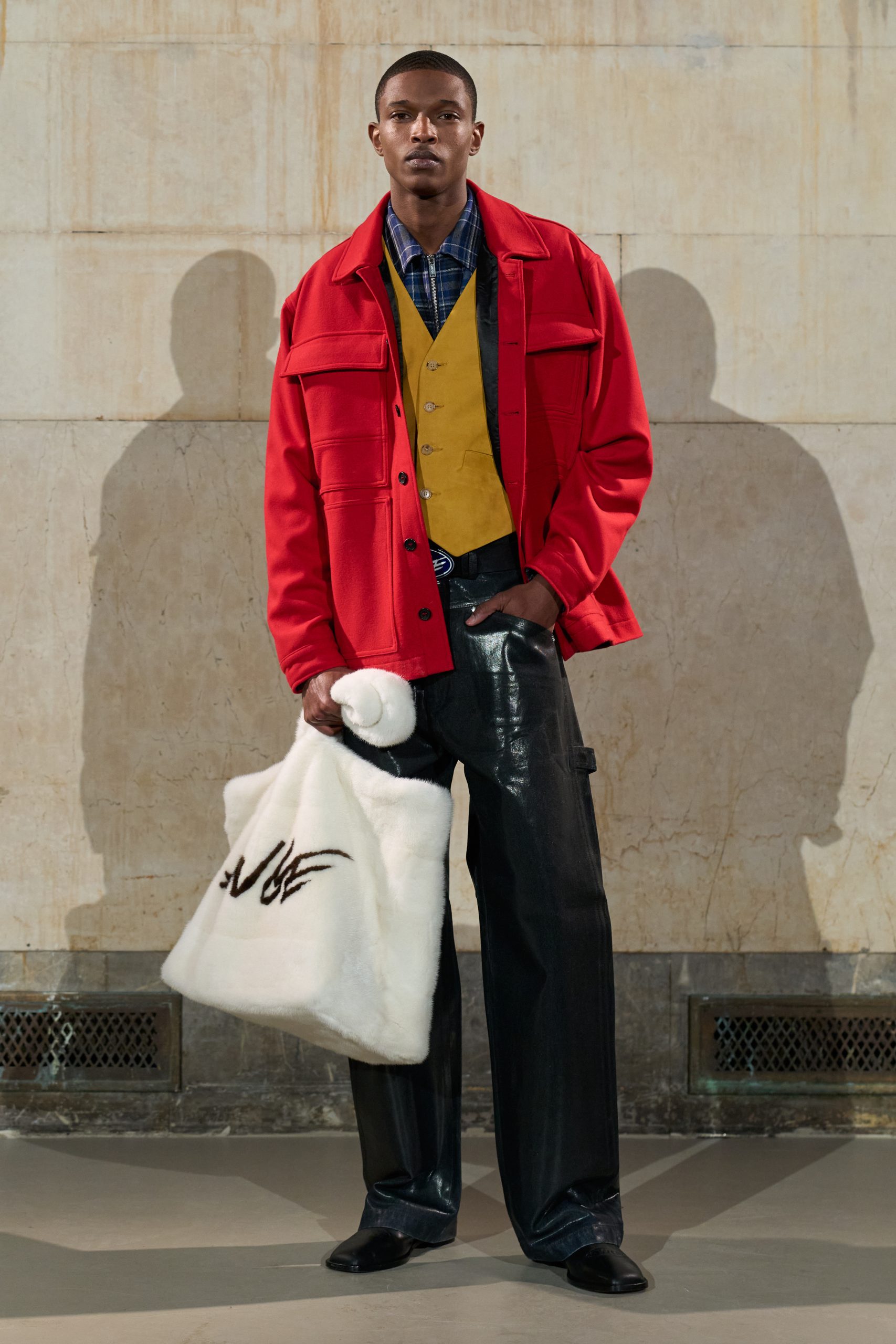 A male model wearing a red jacket and black pant look from AWGE's Fall Winter 2026 runway show.