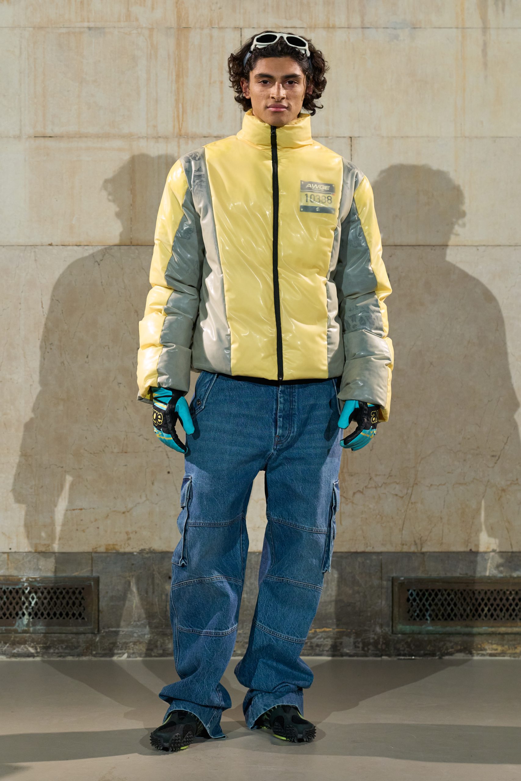 A male model wearing a yellow and blue outerwear look from AWGE's Fall Winter 2026 runway show.