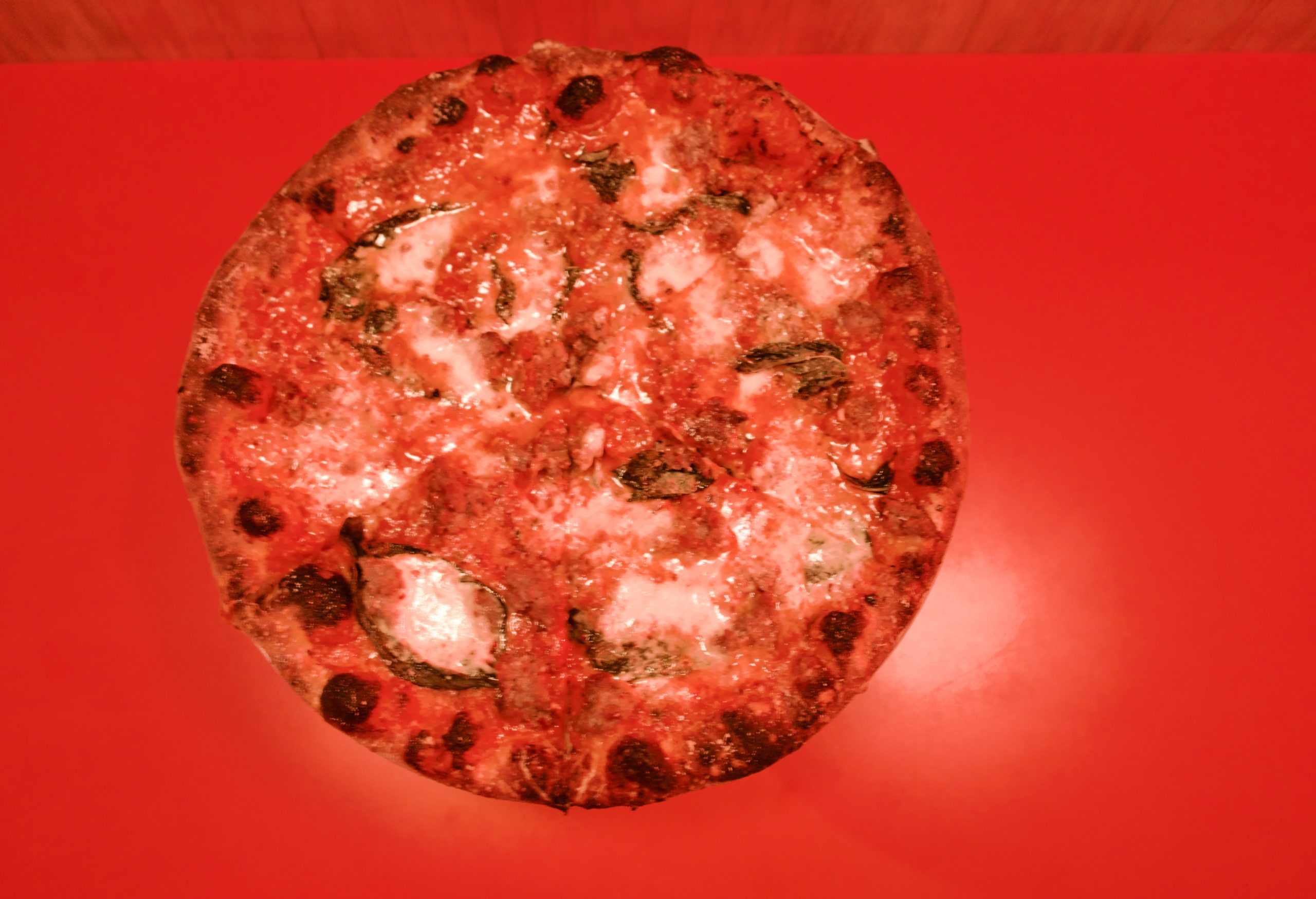 An overhead view of a pizza in red light at Cents Pizza.
