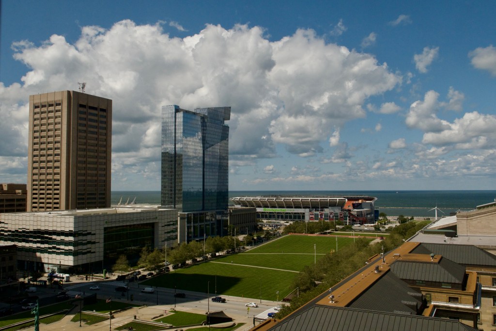 An aerial view of Cleveland with tall buildings, a baseball stadium and a waterfront area.