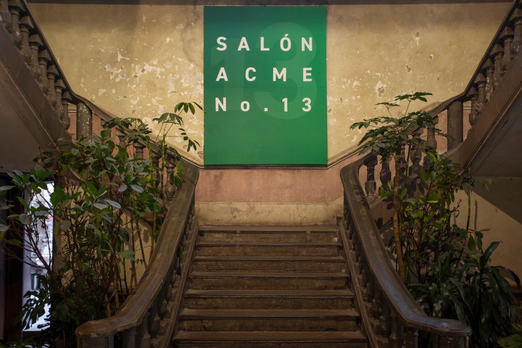 A stone stairway leading to a green banner that says SALON ACME No. 13.