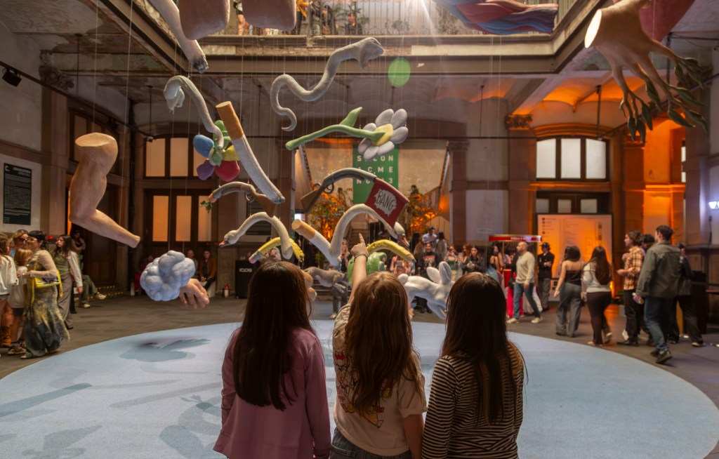 A group of three children looking at a large hanging sculpture at Salon ACME in Mexico City.