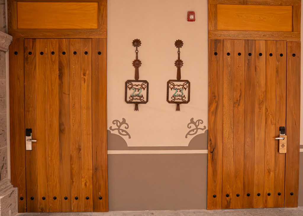 Two wooden doors at La Casona with patinated copper room numbers
