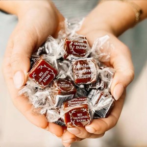 Two cupped hands holding wrapped caramels from Bee Grateful Farm