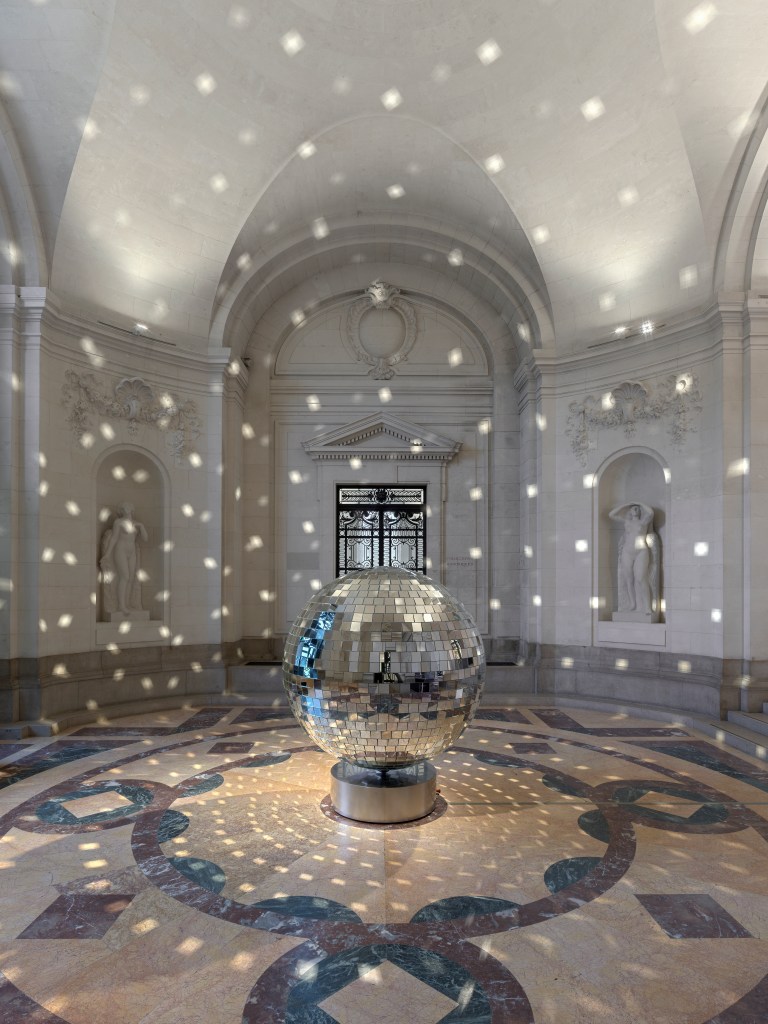 A large disco ball casting reflective light onto a room in MAH Genève.