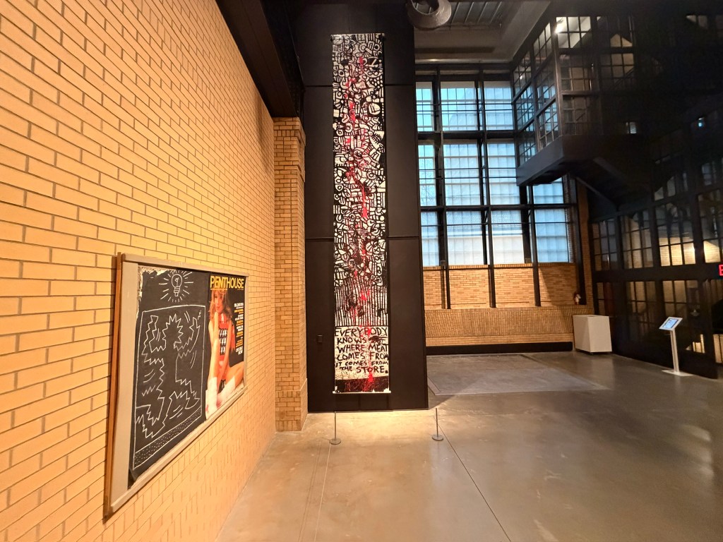 A very tall work in black with red and a subway drawing by Keith Haring