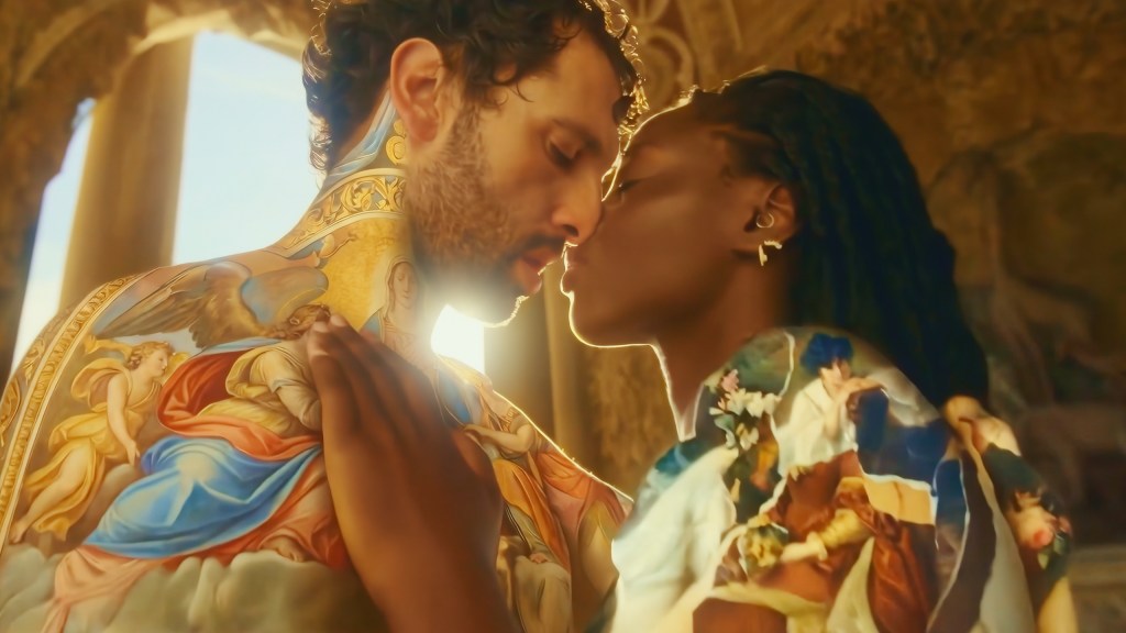 A man and a woman, whose bodies are covered with images of paintings, are leaning in about to kiss.