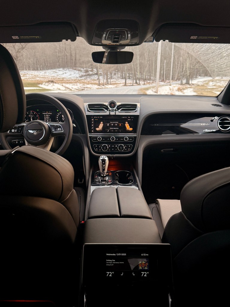 A view of the 2025 Bentley Bentayga EWB Azure front seats and dashboard, shot from the back seat inside the car.