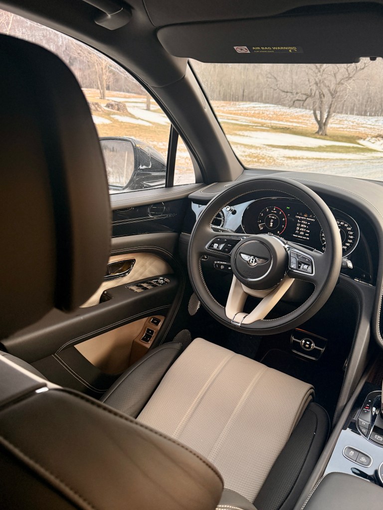 A high angle shot from inside the 2025 Bentley Bentayga EWB Azure, looking down at the perforated leather driver's seat.