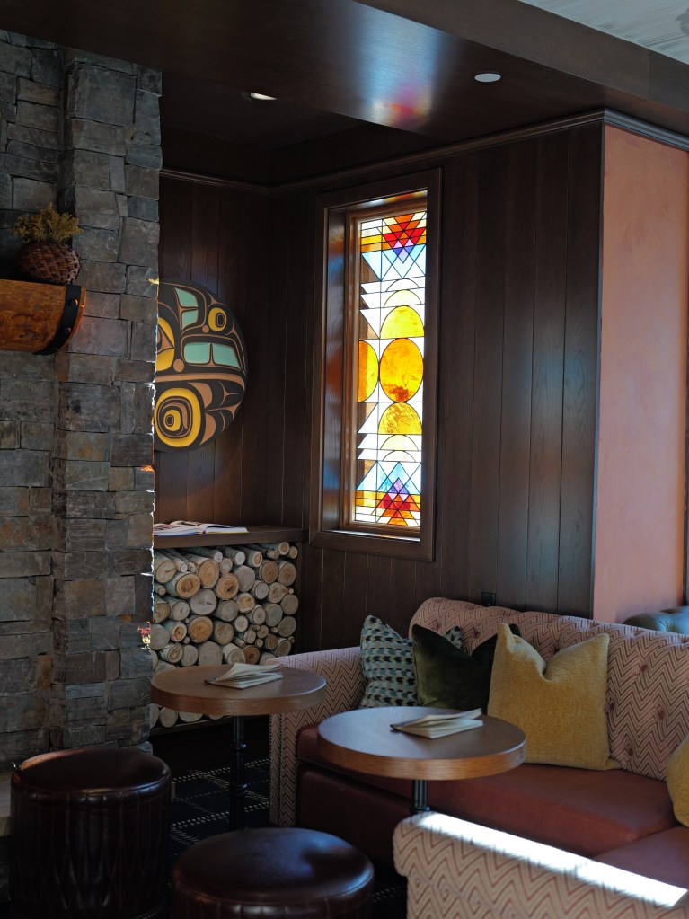 A corner of the living room with a custom stained-glass window, wood paneled walls and a comfortable couches.
