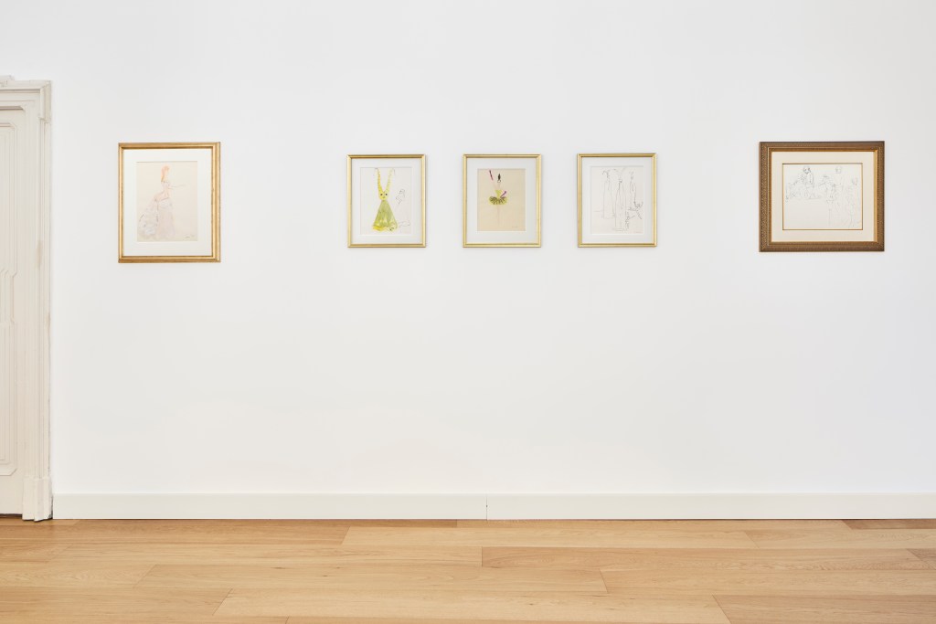 A white-walled gallery room with light wood floors and five Leonor Fini paintings on the wall. 