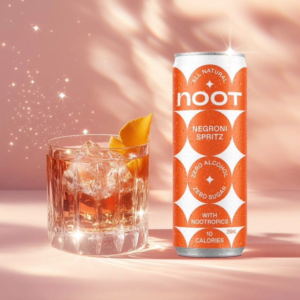 A cocktail in a glass with an ice cube and an orange twist next to a can of Noot's Negroni Spritz