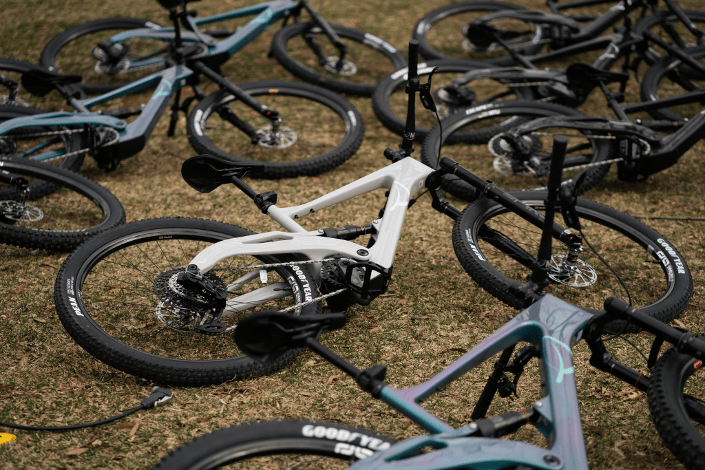 Several Lauf eElja bikes of different colors lying on their side on a grassy area.