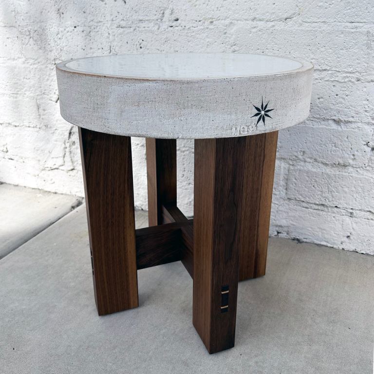 A M Quan table has a round, thick ceramic top with a star on the side on top of four legs