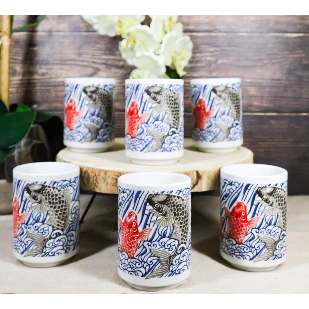 Six yin yang red black koi fish by waterfall yunomi tea cups on a table with an orchid