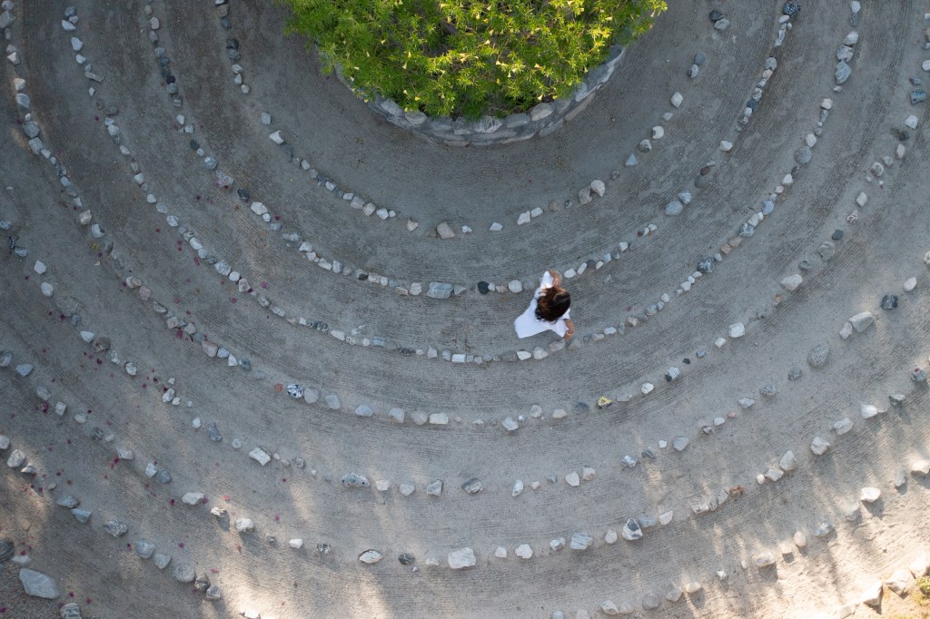 An overhead shot of a woman walking in a meditation labryinth.