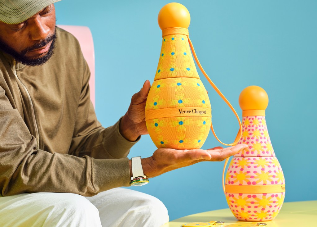 Designer Yinka Ilori holds two colorful Veuve Clicquot bottle holders he's designed