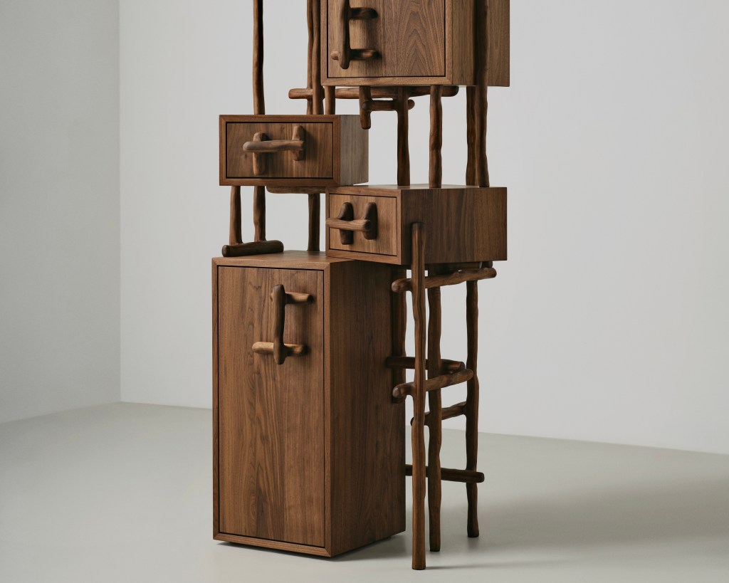 A wood cabinet with multiple carved doors and handles stands on a plain floor