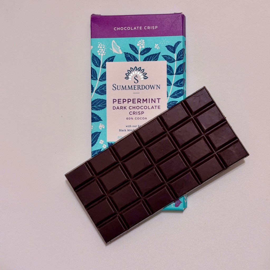 A Summerdown Peppermint Dark Chocolate Crisp bar laying on top of it's packaging