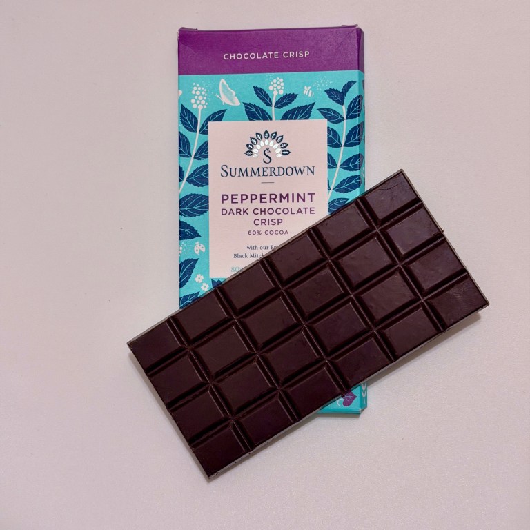 A Summerdown Peppermint Dark Chocolate Crisp bar laying on top of it's packaging