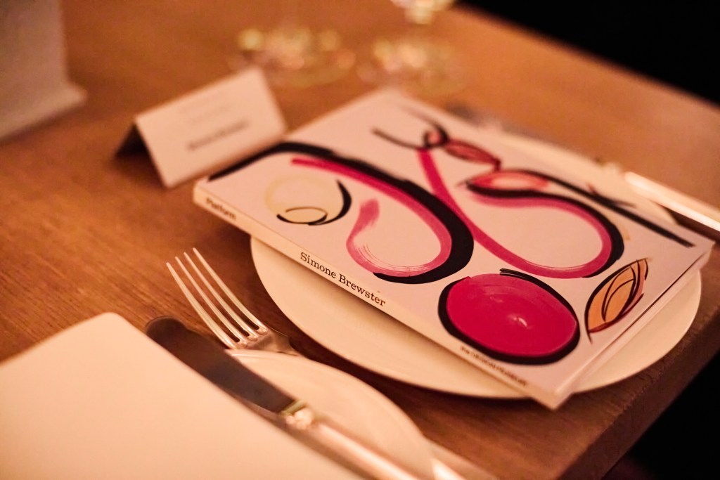 A soft focus image of a Simone Brewster book sitting on a white plate on a wooden table.