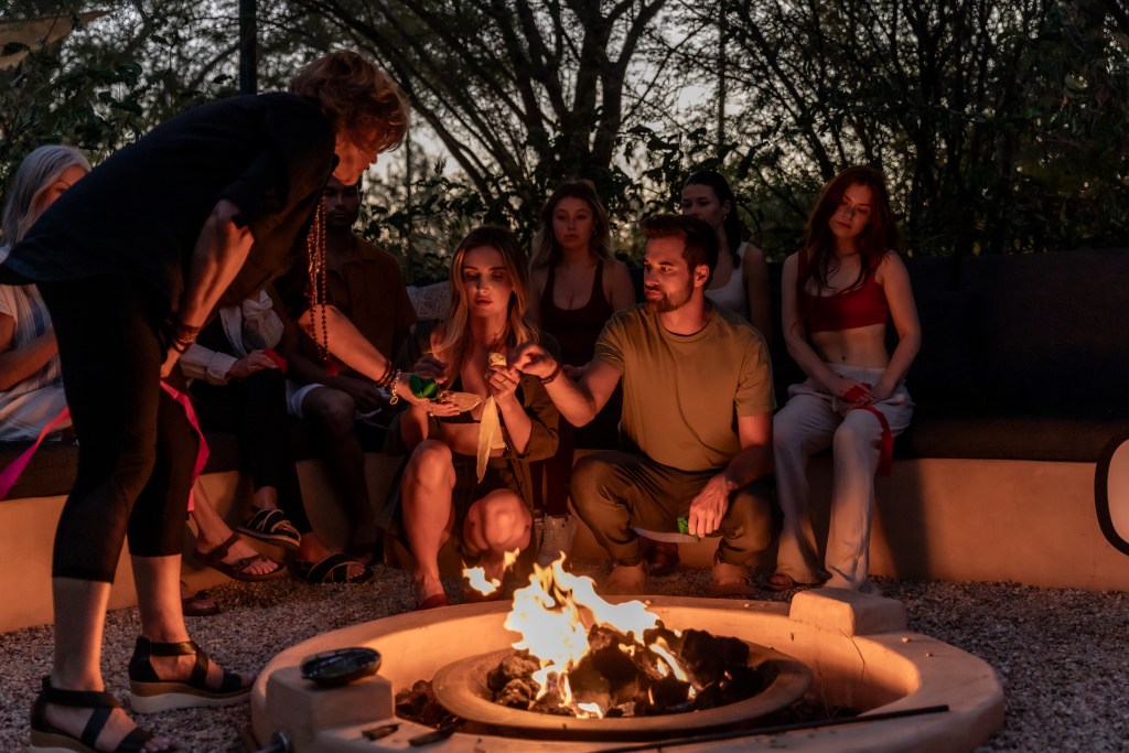 A group of people surrounding a fire with an instructor showing them how to use their prayer ties.