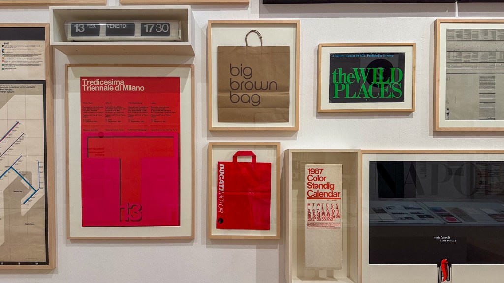 A salon style wall of framed graphic designs by Lella and Massimo Vignelli.