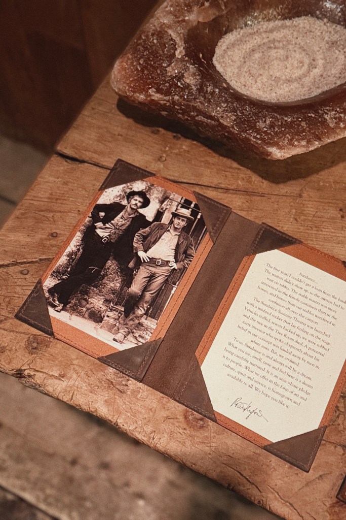 A black and white photo of Robert Redford sits on a leather folder with a hand-written note.