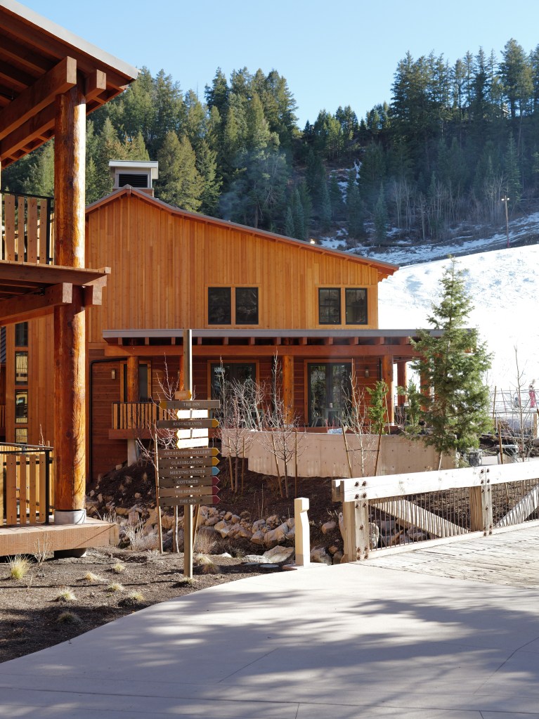 An exterior view of the wooden Inn at Sundance Mountain Resort with trees and mountains behind it.