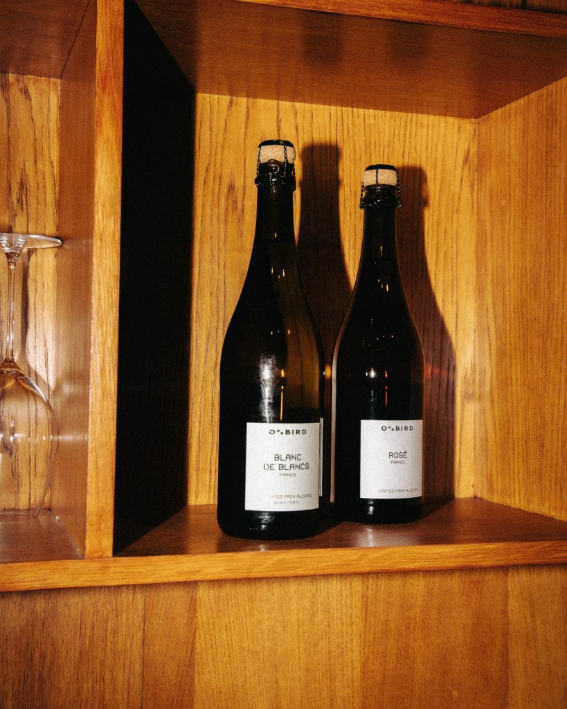 A wood shelf with two bottles of Oddbird wine on it and heavy shadows.