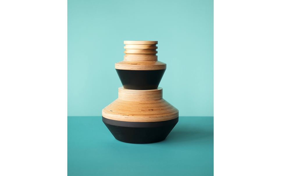 A wooden sculptural piece by Simone Brewster on a turquoise background.