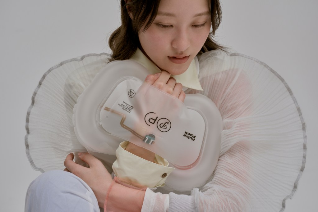 a seated woman in a white dress has a Pulse Pack around her hand